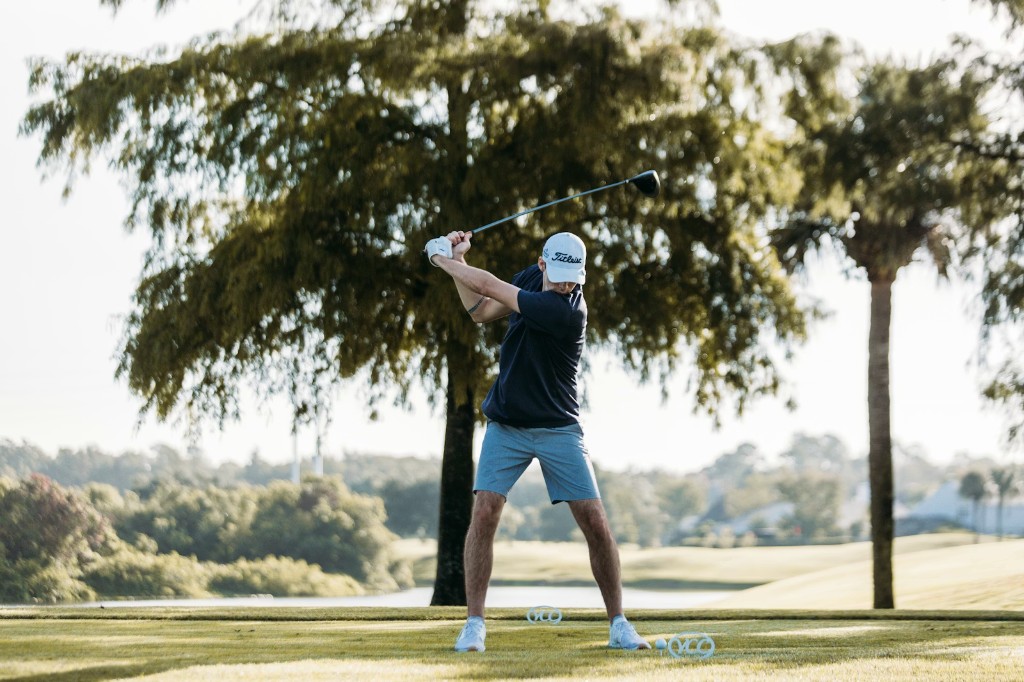 Golfer mid-swing on a sunny golf course